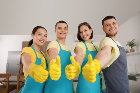 Group of young janitors showing thumbs-up in kitchenの写真素材