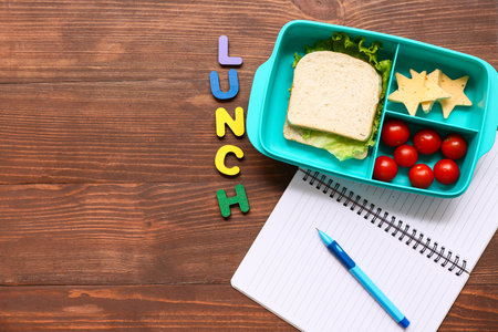 Lunch box with tasty food and school stationery on wooden background, top viewの写真素材