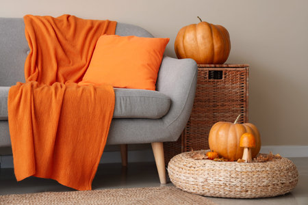 Interior of cozy living room with sofa, pouf and pumpkins