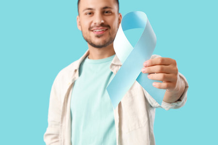 Young man with blue ribbon on color background, closeup. Prostate cancer awareness conceptの写真素材