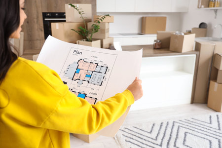 Beautiful woman with house plan in kitchen on moving day, closeup