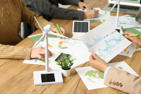 Business team with wind turbine model working on green energy strategies during office meetingの写真素材