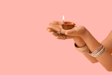 Female hands with burning candle on pink background. Divaly celebrationの写真素材