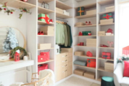 Modern wardrobe with stylish Christmas clothes and gift boxes, blurred viewの写真素材
