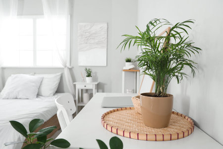 Laptop with decor on table near comfortable bed at home, closeup