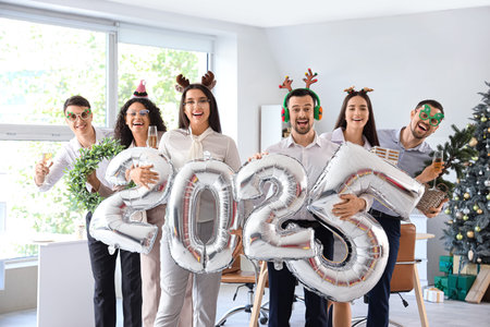 Business people with champagne and figure 2025 made of balloons celebrating New Year at party in...