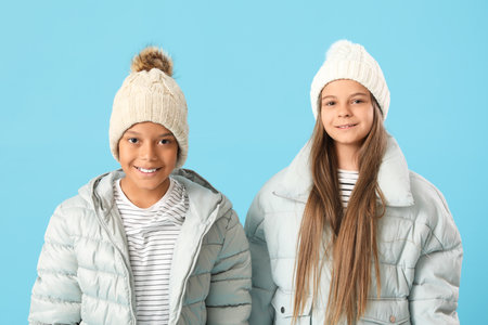 Cute little happy children in winter clothes on blue backgroundの写真素材