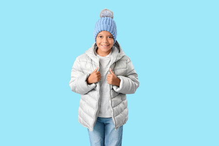Cute little happy African-American boy in winter clothes on blue backgroundの写真素材