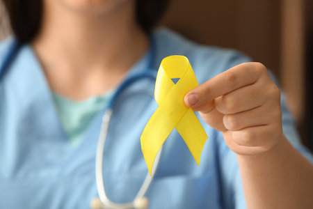 Doctor holding yellow ribbon, closeup. Sarcoma concept.の写真素材