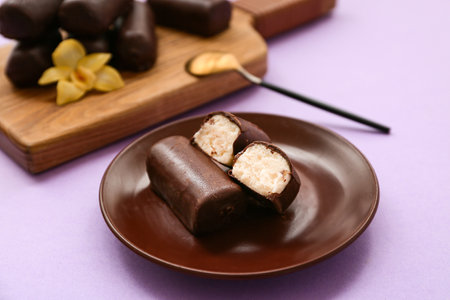Plate with tasty chocolate glazed curd snacks with vanilla flavor on lilac backgroundの写真素材