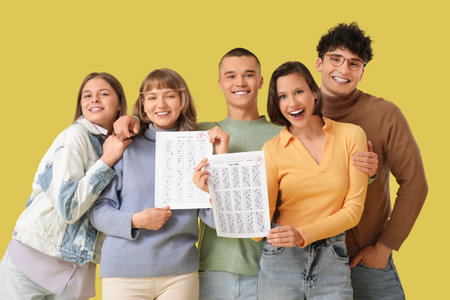 Group of students with results of exam on yellow backgroundの写真素材