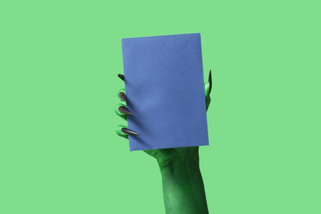 Green hand of witch with envelope on color background. Halloween celebrationの写真素材