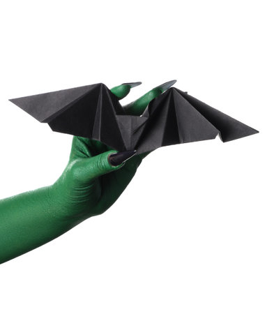 Green hand of witch with bat made of paper on white background. Halloween celebration