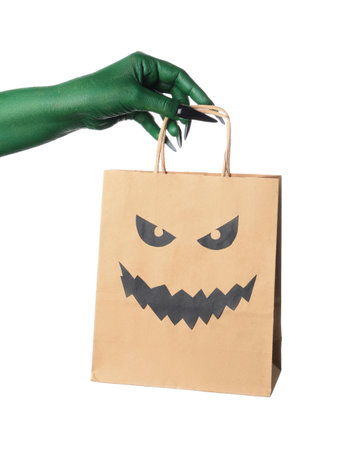Green hand of witch with shopping bag on white background. Halloween celebrationの写真素材
