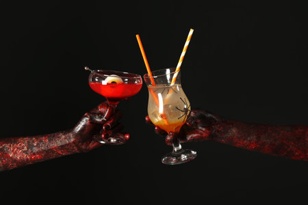 Hands of zombies with glasses of cocktails on black background. Halloween celebrationの写真素材