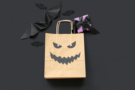 Composition with paper shopping bag, gift box and decorations for Halloween on dark backgroundの写真素材