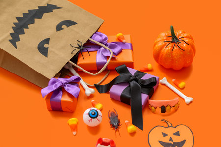 Composition with shopping bag, gifts and decorations for Halloween on orange backgroundの写真素材