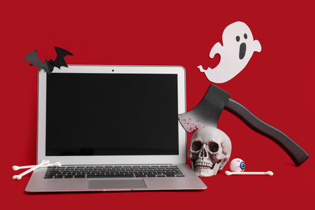 Modern laptop with different decor for Halloween on red backgroundの写真素材