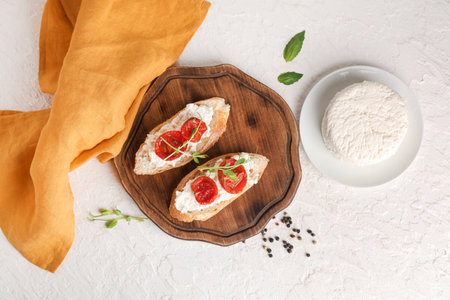 Wooden board of tasty tomato bruschetta with ricotta and peppercorn on white backgroundの写真素材