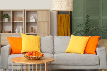 Stylish interior of living room with sofa and apricots in bowl on coffee table