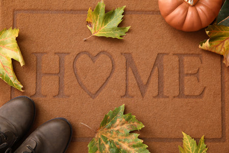 Autumn leaves with pumpkin and shoes on doormat, top viewの写真素材