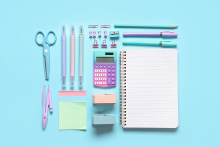 Blank notebook with different stationery supplies on blue background