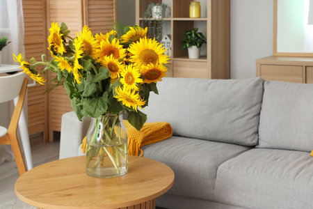 Stylish living room with gray sofa and vase of sunflowers bouquet on coffee tableの写真素材
