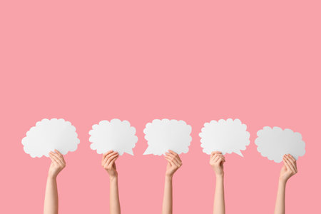 Female hands with speech bubbles on pink backgroundの写真素材