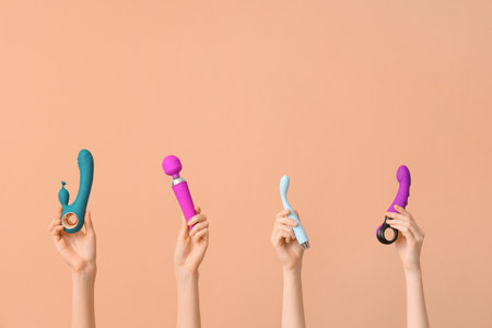 Female hands with different vibrators on brown backgroundの写真素材