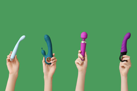Female hands with different vibrators on green backgroundの写真素材