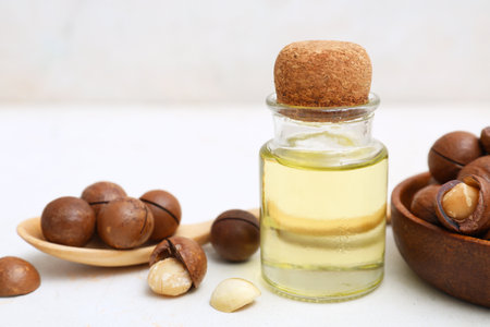 Bottle of essential oil and macadamia nuts on light background, closeupの写真素材