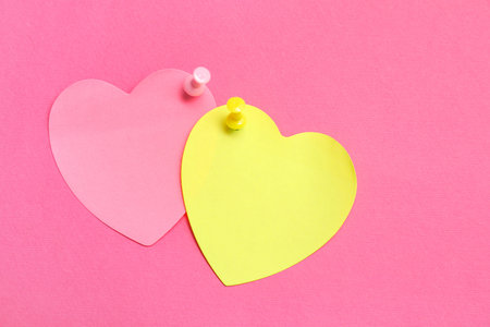 Paper notes in shape of heart pinned on pink backgroundの写真素材
