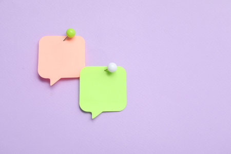 Paper notes in shape of speech bubble pinned on lilac backgroundの写真素材