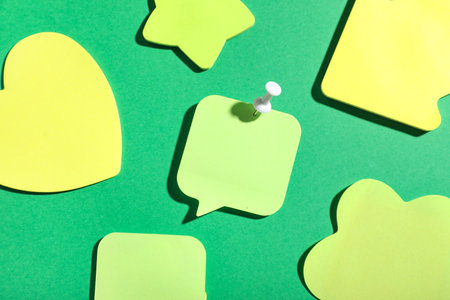 Paper note in shape of speech bubble pinned on green backgroundの写真素材