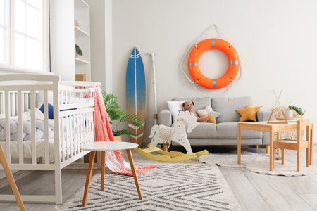 Crib, kid's table with chair, rocking horse and lifebuoy ring on wall in nursing roomの写真素材