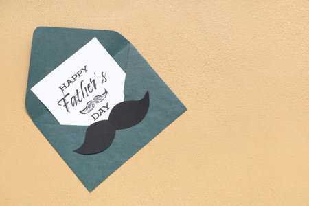 Paper in envelope with text HAPPY FATHER'S DAY on beige background. Top view