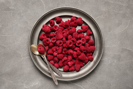 Plate of dehydrated raspberries on gray background
