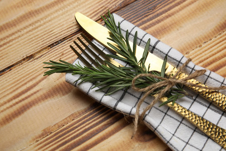 Stylish table setting with napkin, cutlery and rosemary on wooden backgroundの写真素材