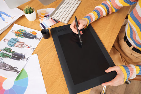 Female graphic designer working with tablet at table in office, closeupの写真素材
