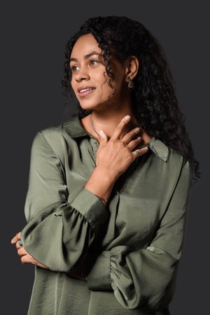 Beautiful young happy African-American woman with stylish jewelry on black background