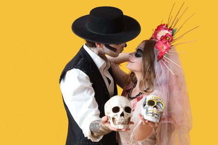 Young happy couple dressed for Mexico's Day of the Dead (El Dia de Muertos) with painted skulls on...