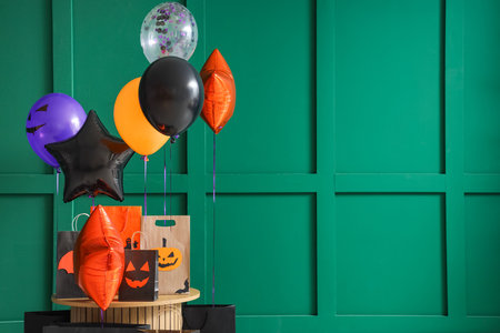 Colorful Halloween balloons with shopping bags on table near green wallの写真素材