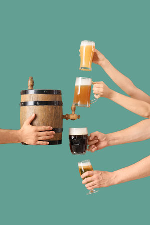 Male hands with barrel, glasses and mugs of cold beer on green background. Octoberfest celebrationの写真素材
