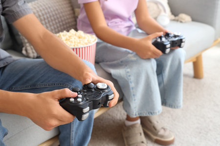Teenage boy with his sister playing video game at home, closeup