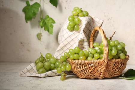 Wicker basket with sweet ripe grapes on white backgroundの写真素材