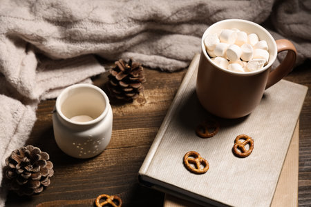 Beautiful composition with books, warm sweater, winter decor and cup of cocoa on brown wooden backgroundの写真素材