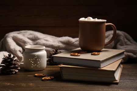 Beautiful composition with books, warm sweater, winter decor and cup of cocoa on brown wooden backgroundの写真素材
