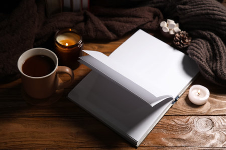 Beautiful composition with book, winter decor, warm clothes and cup of cocoa on brown wooden...