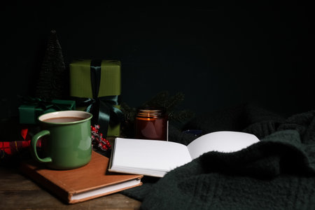 Winter composition with books, Christmas gift boxes, cup of tea and warm sweater on brown wooden backgroundの写真素材