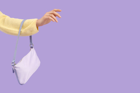 Female hand with stylish lilac bag on purple background, closeup